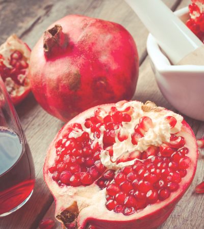 Pomegranate, juice in glass, mortar and pestle on wooden rustic table